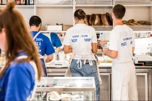 Four staff members working behind a service counter at Fabbrica, featuring branded t-shirts and aprons against a commercial kitchen interior.