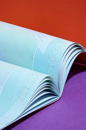 Abstract close-up of folded, patterned paper in light turquoise, with orange and purple background. Geometric, textural aesthetic.