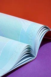 An open passport with perforated pages and blue patterns resting on a purple and orange background.