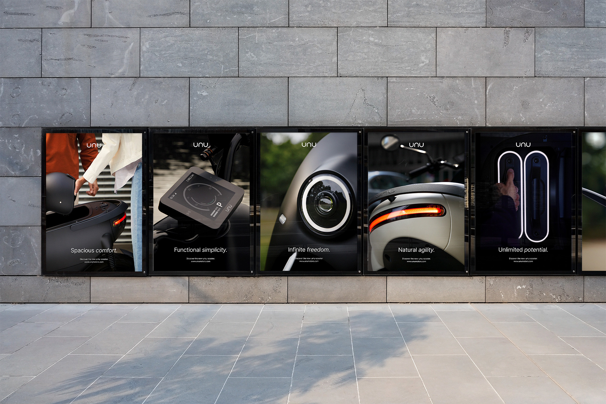 Five posters on a gray brick wall advertise scooters, highlighting features like spacious comfort and unlimited potential in a modern design.