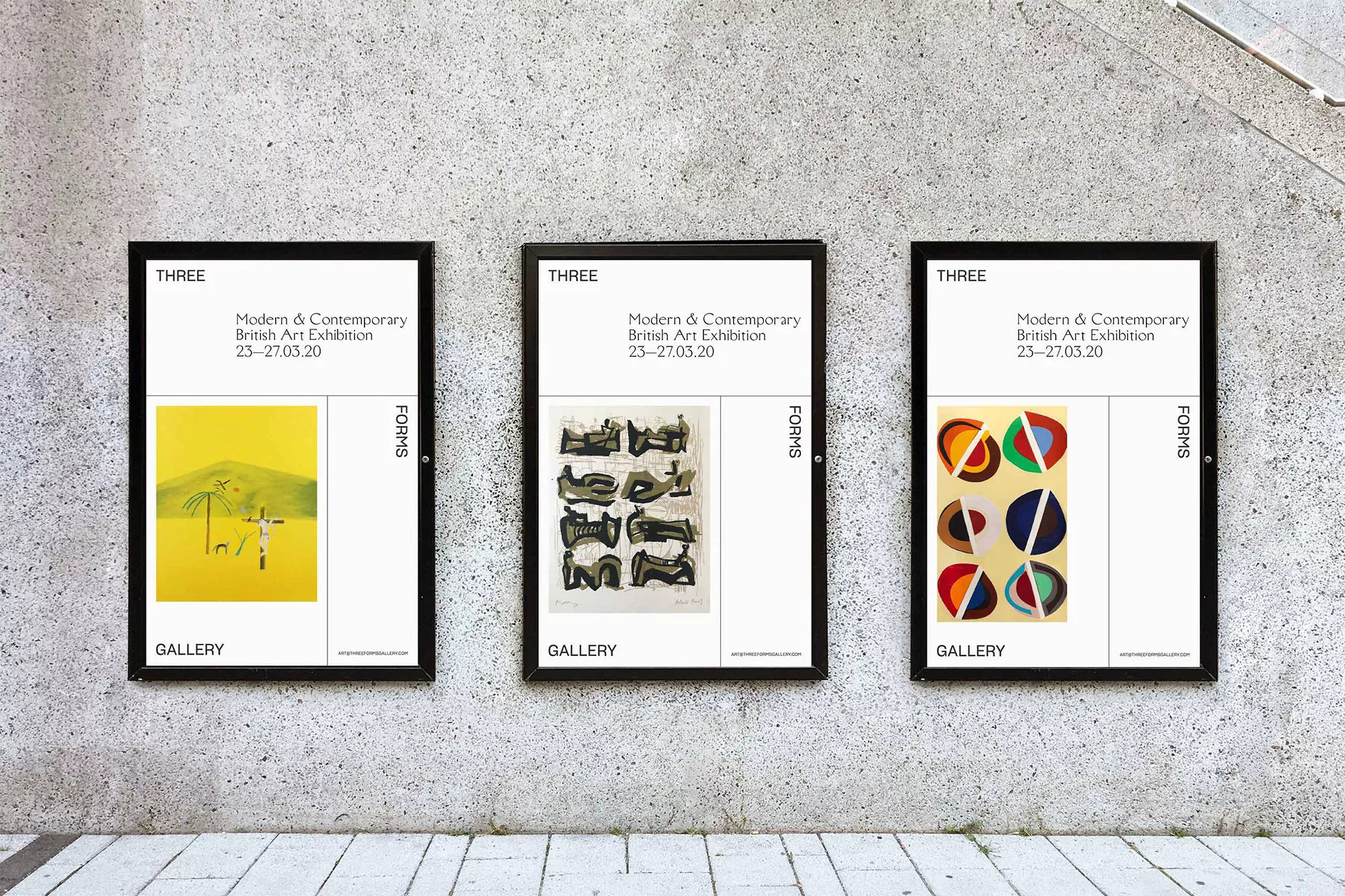 Three framed art posters displaying a modern British art exhibition hang in a row on a grey concrete wall inside an art gallery.