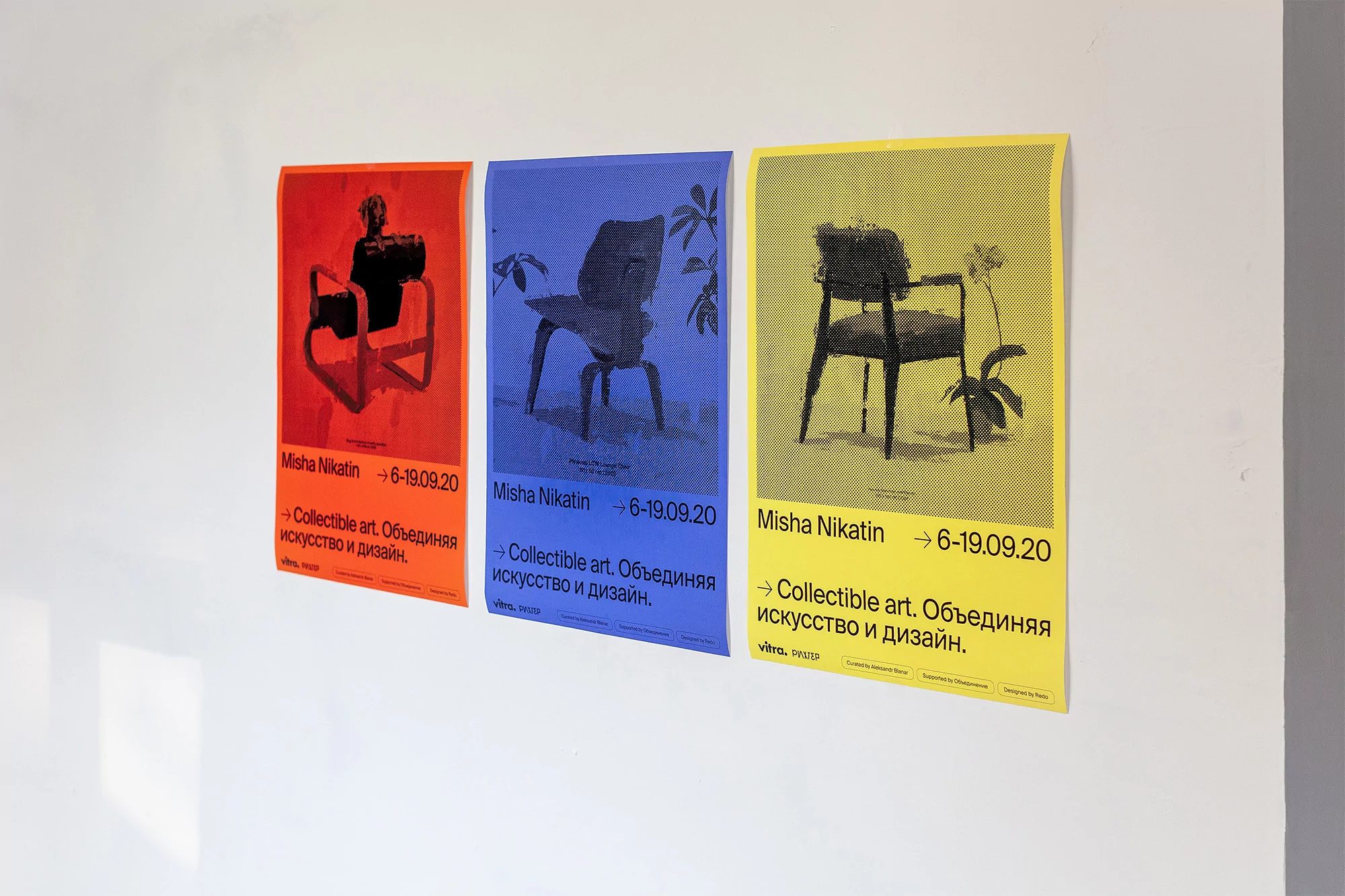 Three colorful art posters featuring chair designs hang on a white wall, promoting an exhibition named Misha Nikatin, 6-19.09.20.