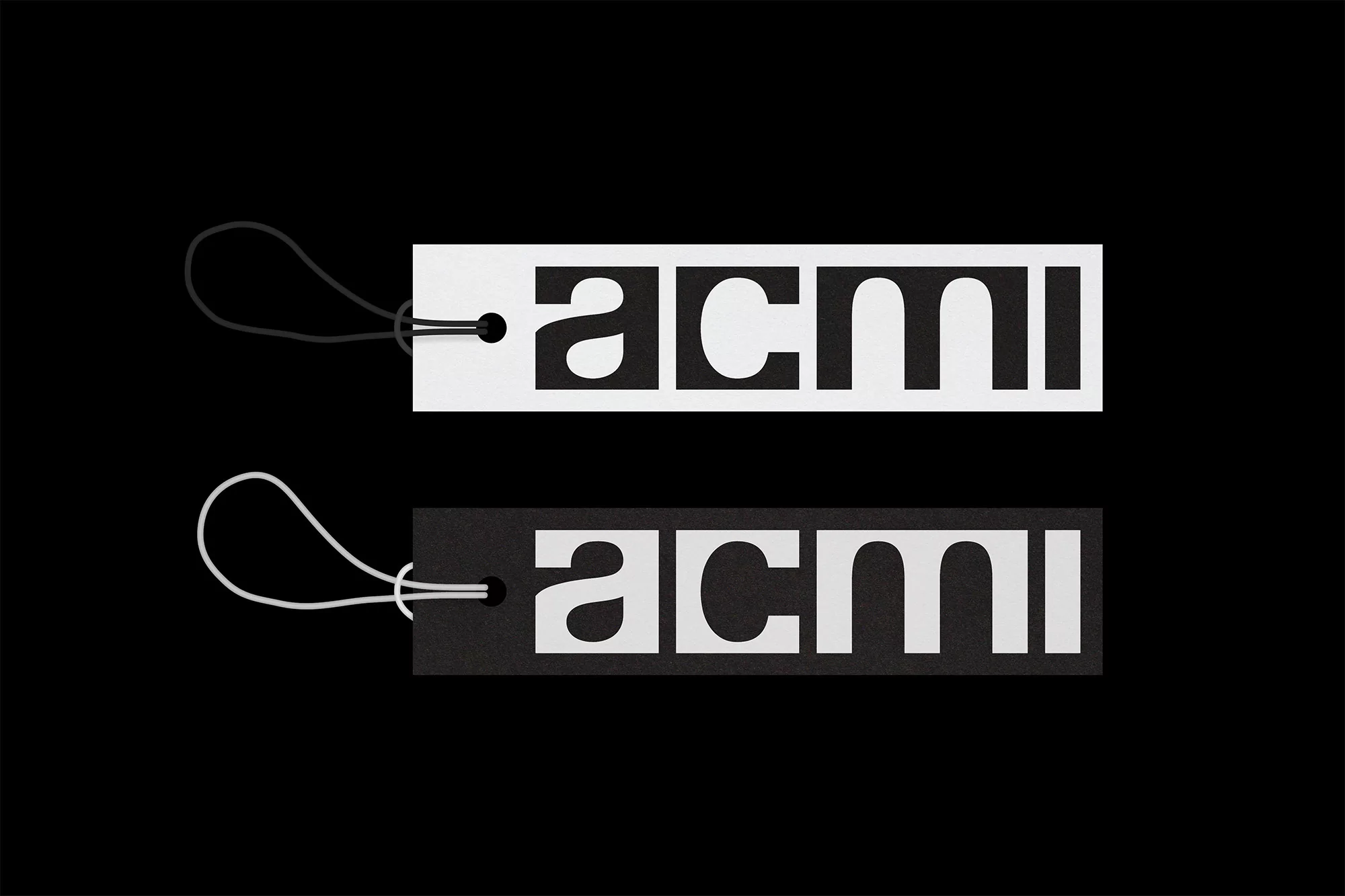 Two tags, one white with black text and one black with white text, both displaying the word 'acmi' against a solid black background.