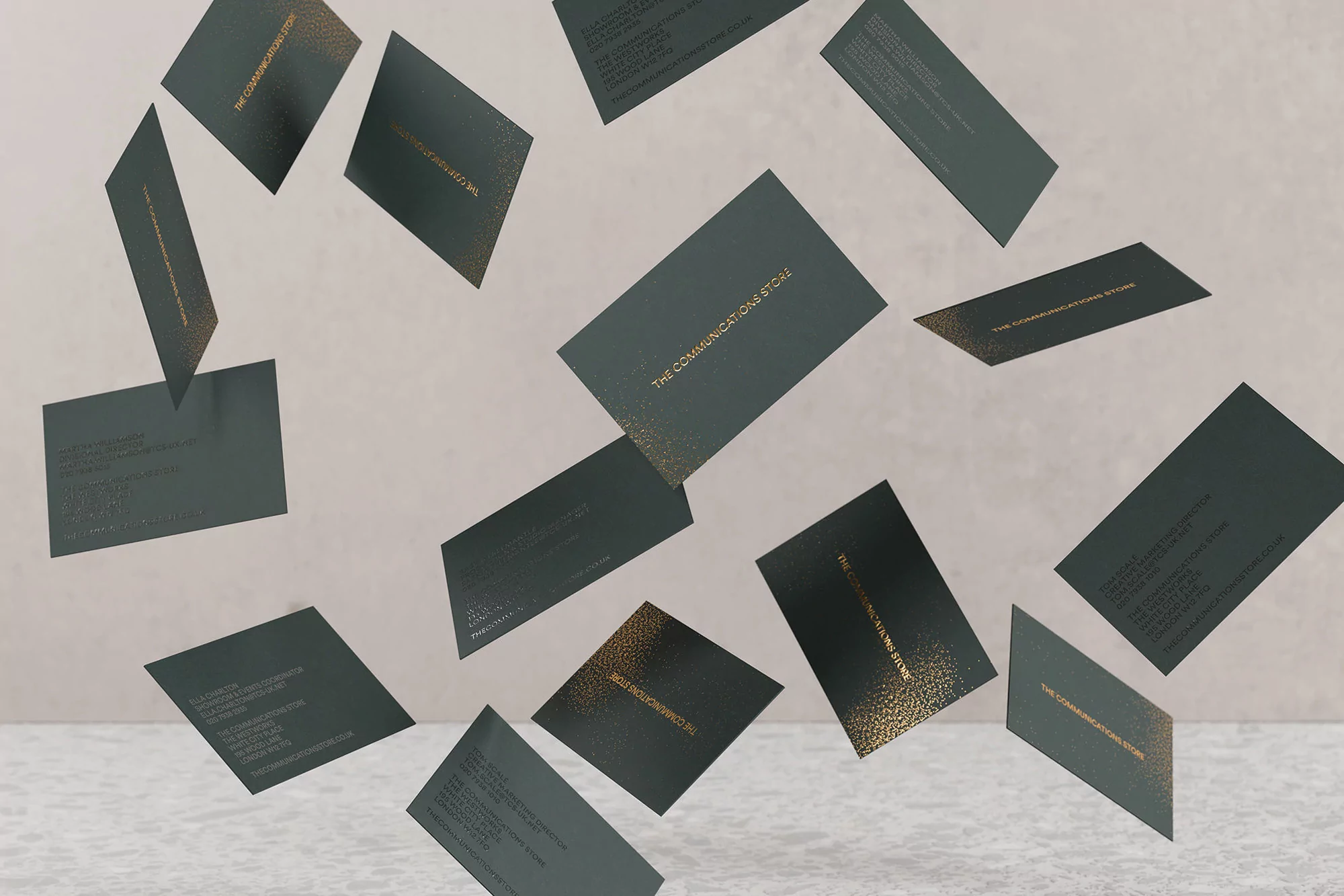 Scattered business cards with a speckled gold design hover against a neutral backdrop, promoting a modern, upscale communication store.