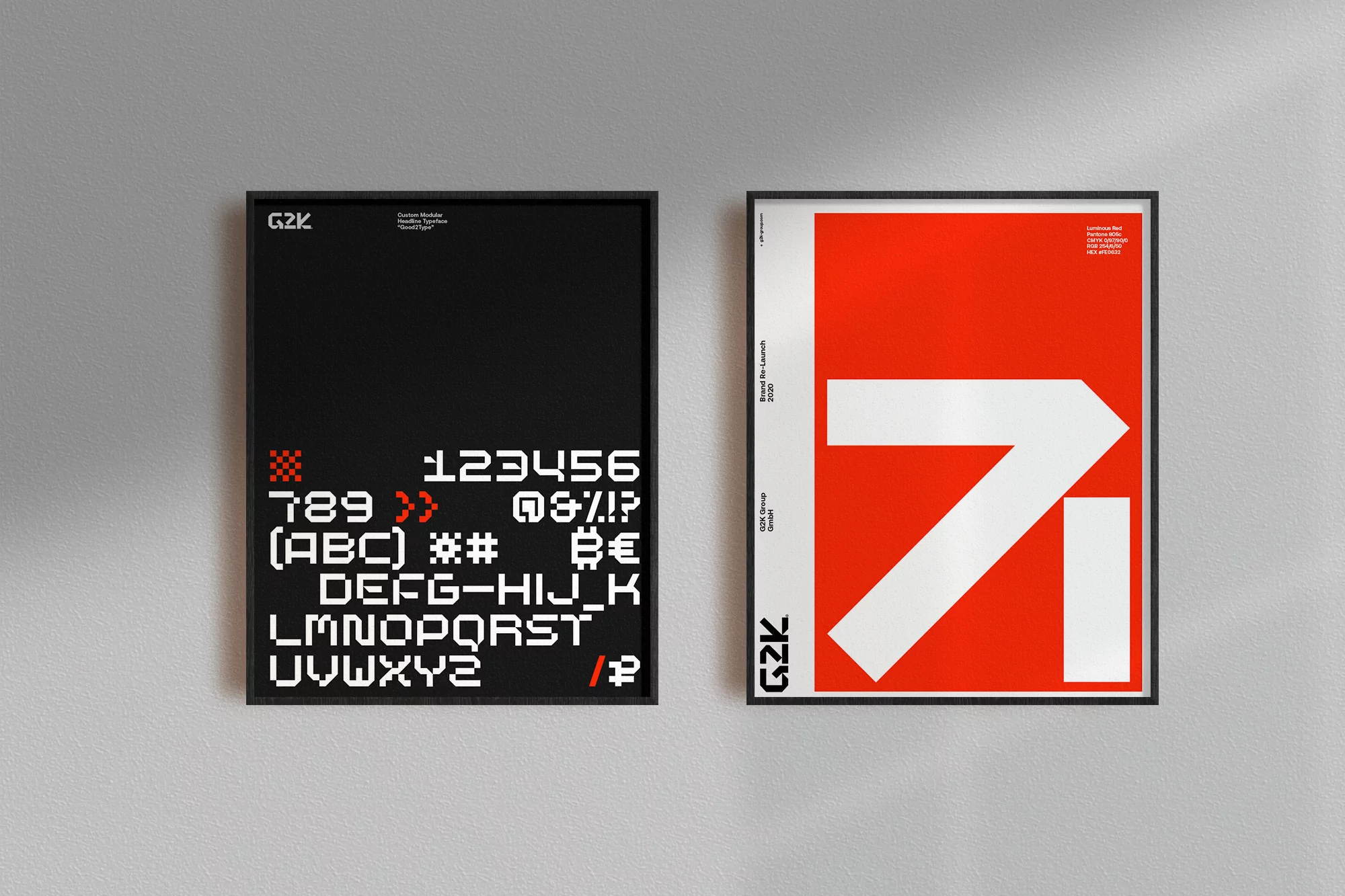 Two framed graphic design posters hang side-by-side on a gray wall, featuring bold typography and geometric shapes in black, red, and white.