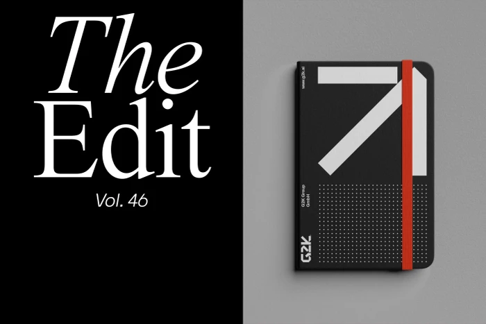 Black notebook with a red elastic band and white graphic cover design placed on a textured grey surface