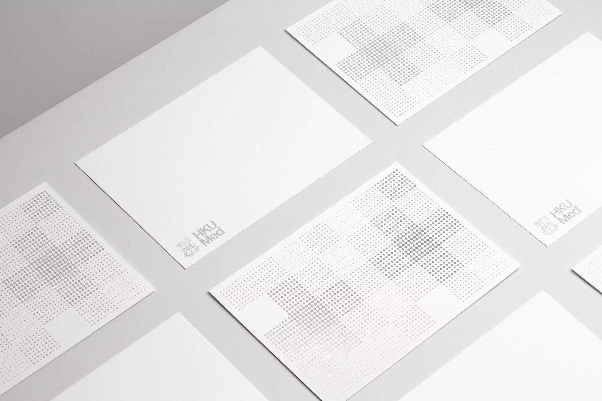 Elevated studio shot of white cards with subtle gray patterns and logos arranged on a white surface, creating a clean and minimalist design.
