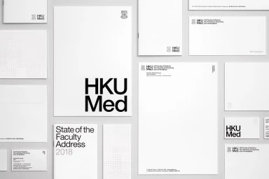 Flat lay of minimalist HKUMed stationery suite including letterhead, envelopes, and brochures on a neutral background