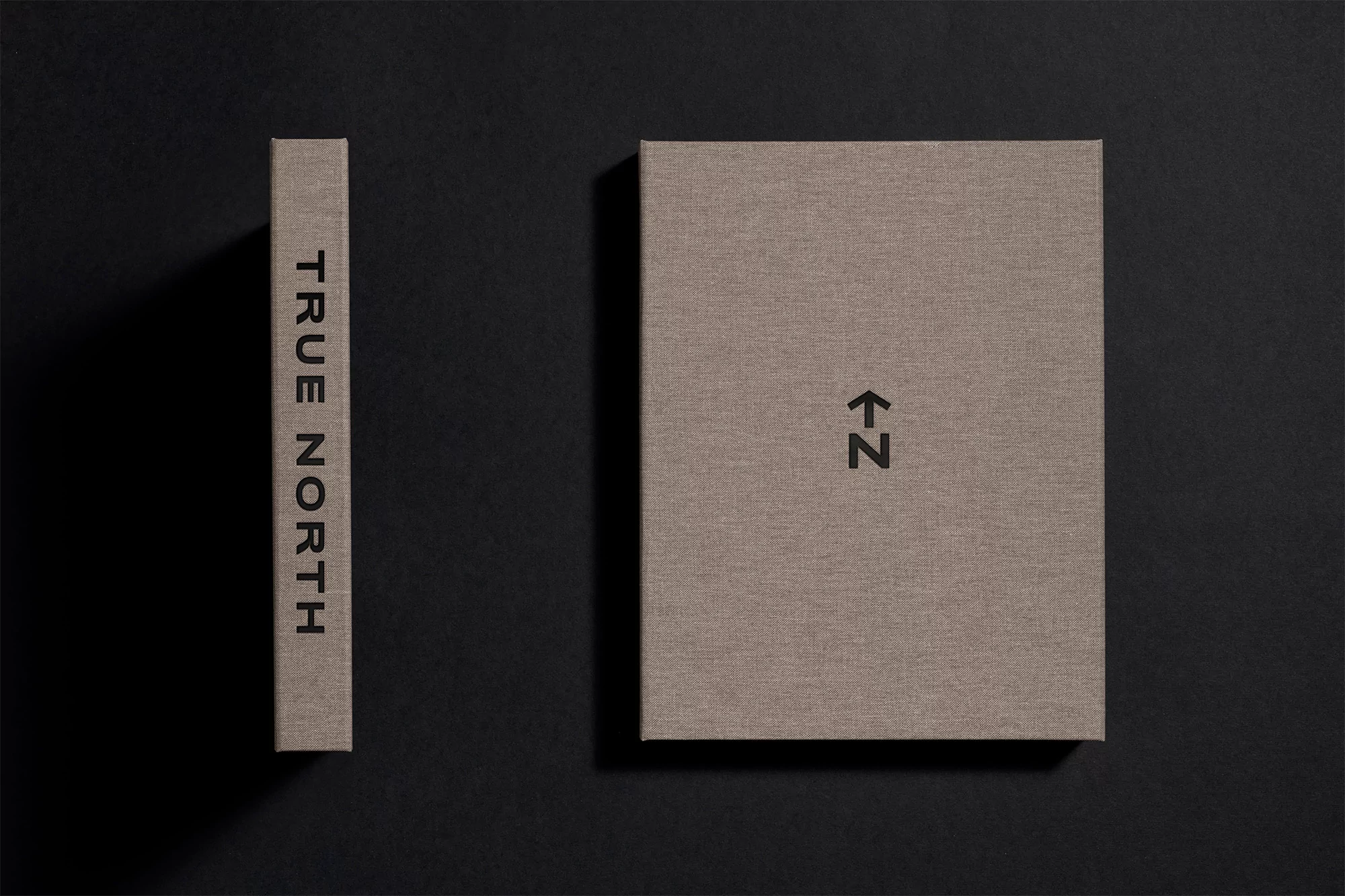 Two books are displayed on a black surface. One is standing, showing its spine, while the other is lying flat, presenting its cover.