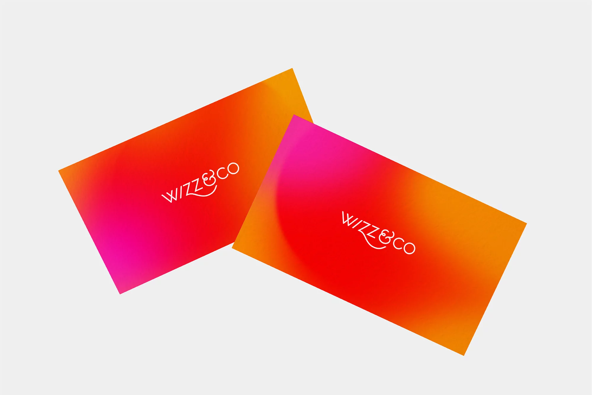 Two business cards with vibrant gradient color fields and white typography resting against a neutral background