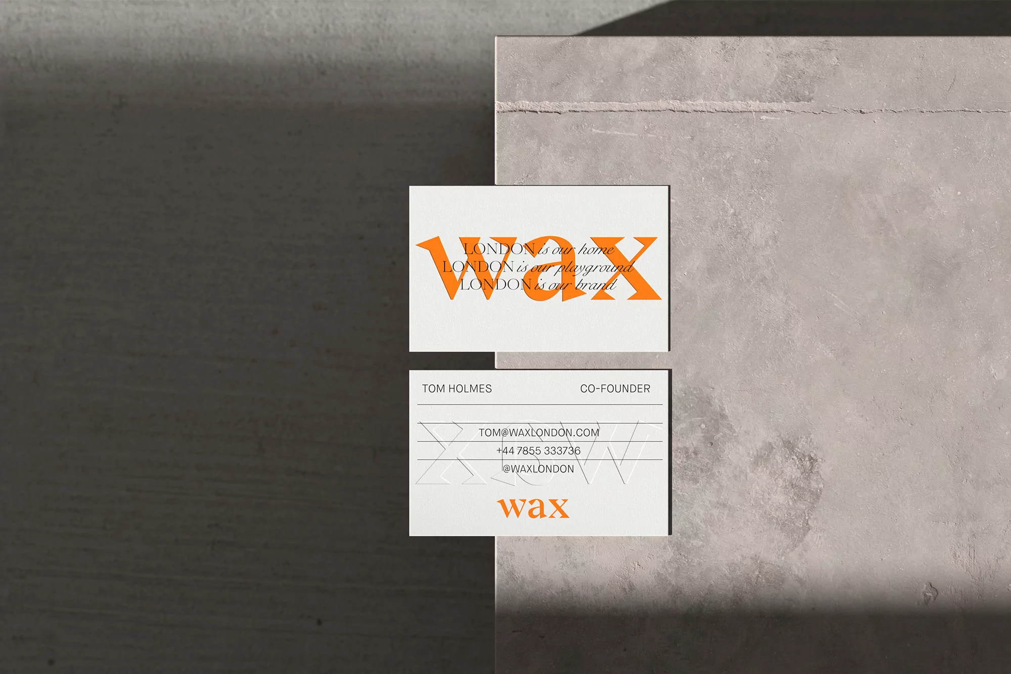Two business cards showcase the Wax London brand against a textured gray backdrop, emphasizing minimalist design and modern aesthetics.