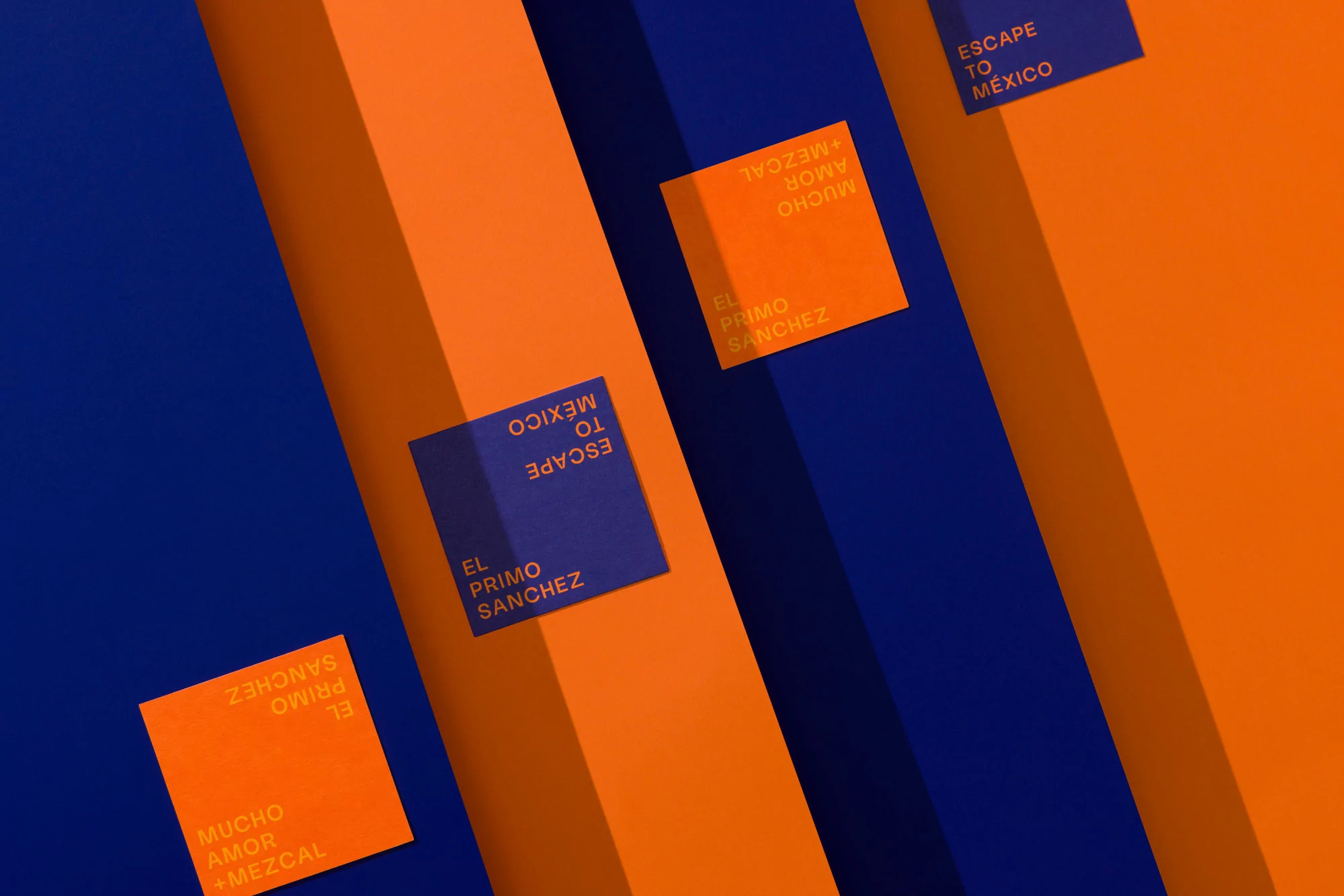 Abstract product shot on a blue and orange surface with El Primo Sanchez printed on square cards, advertising Escape to Mexico.
