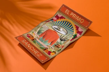 An illustrated print for El Primo Sanchez sits on a vibrant orange surface, casting a sharp shadow with leaf patterns.