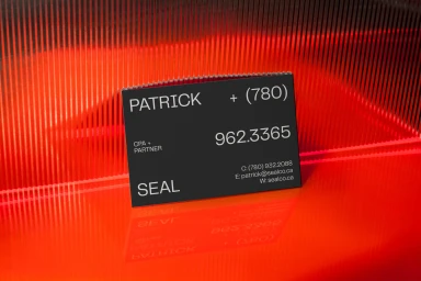 Black business card with white text on a reflective red corrugated surface