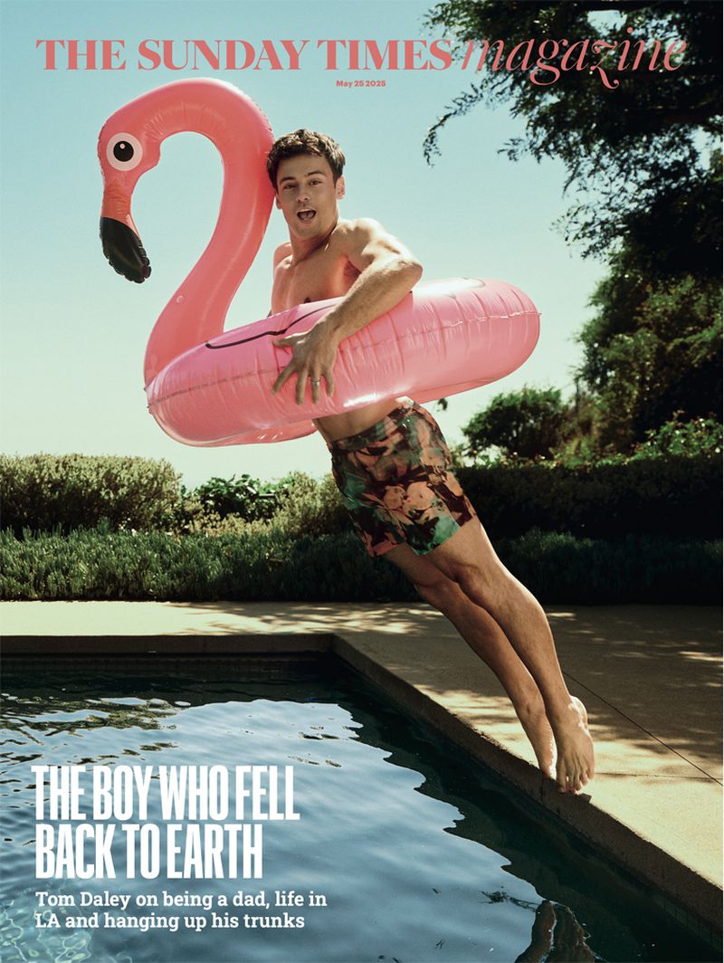 Tom Daley magazine cover features him on pool edge with pink flamingo floatie, floral shorts, blue water, trees in background.