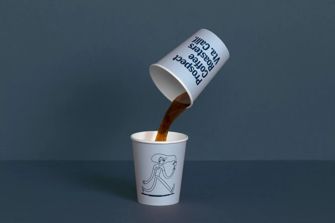 Coffee being poured from a cup labeled 'Prospect Coffee Roasters Vta. Calif.' into a matching cup with a line art illustration.