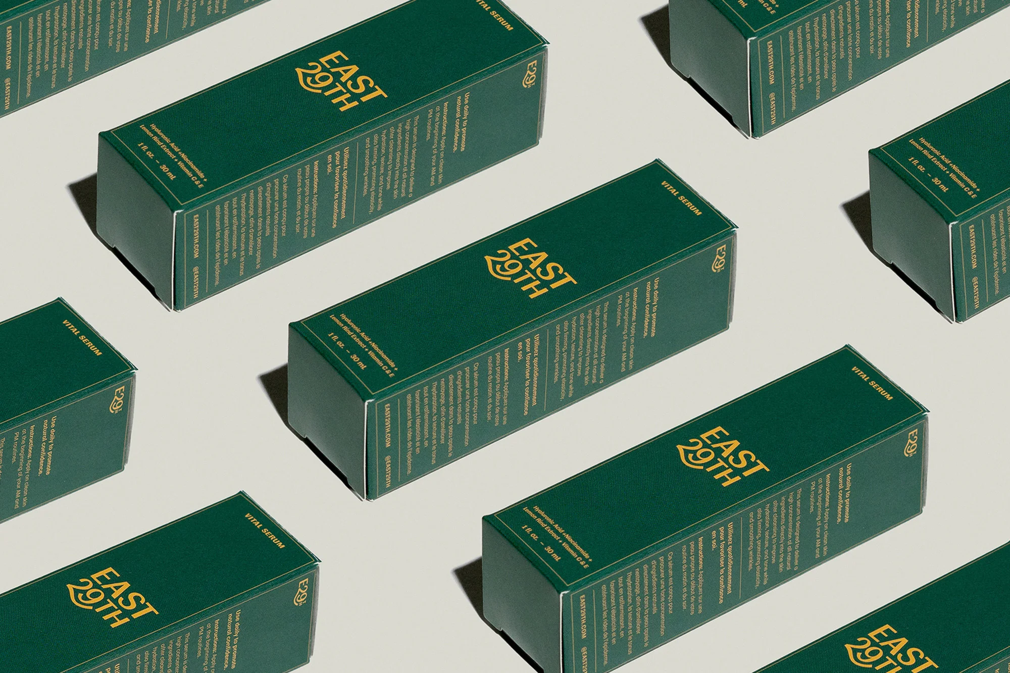 Multiple green and gold EAST 29TH serum boxes arranged in a repeating pattern on a neutral background, product and brand presentation.