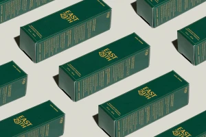 Multiple green rectangular product boxes with gold text arranged diagonally on a light grey background.