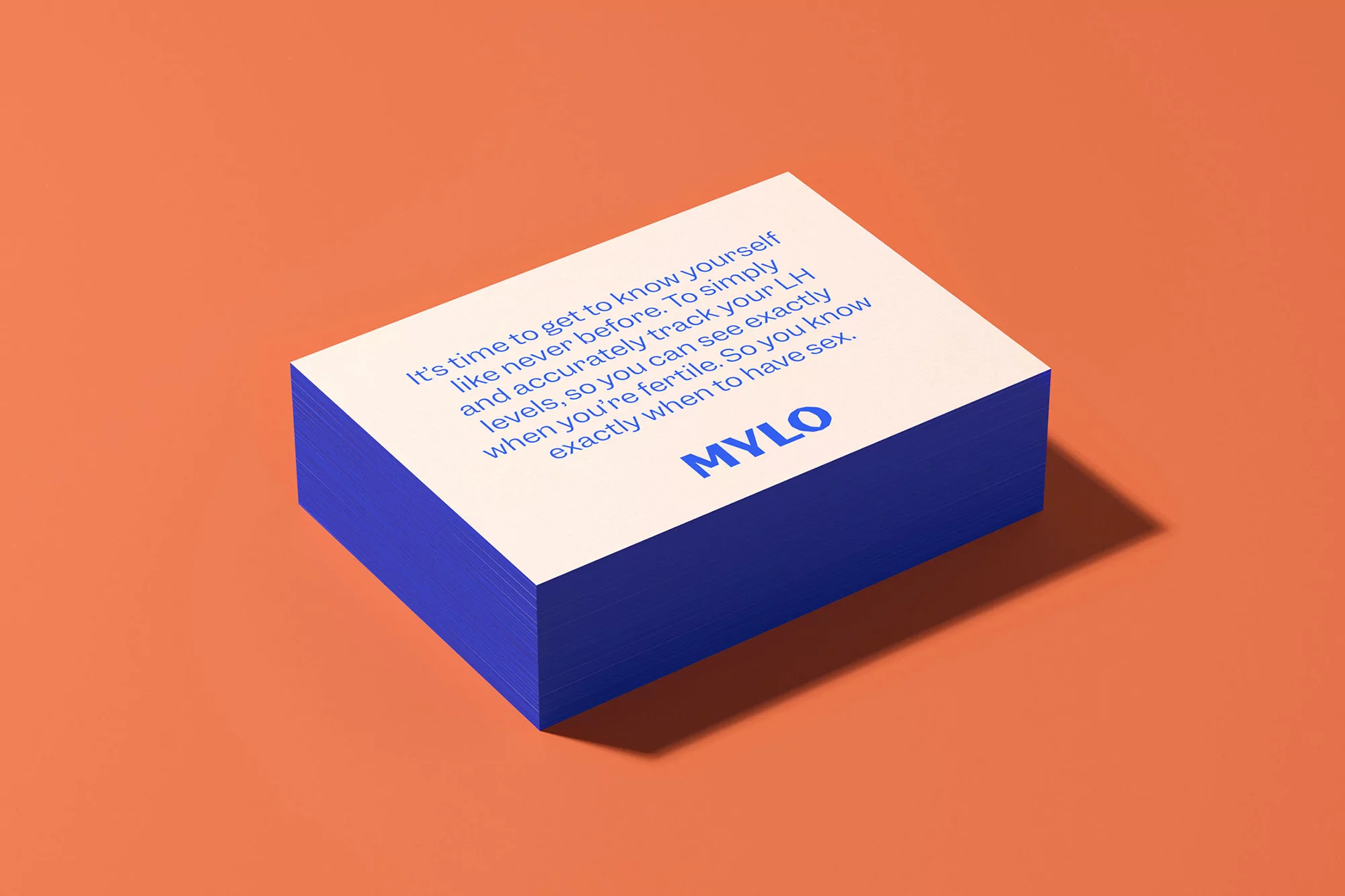 Close-up studio shot of a stack of paper cards with the brand name MYLO and surrounding text displayed against a orange background.