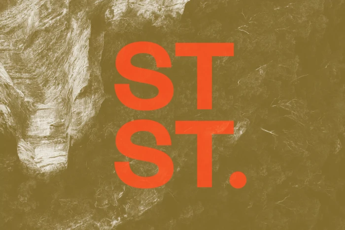 Orange ST. typography overlaid on a textured earth-toned background showing rocky details.