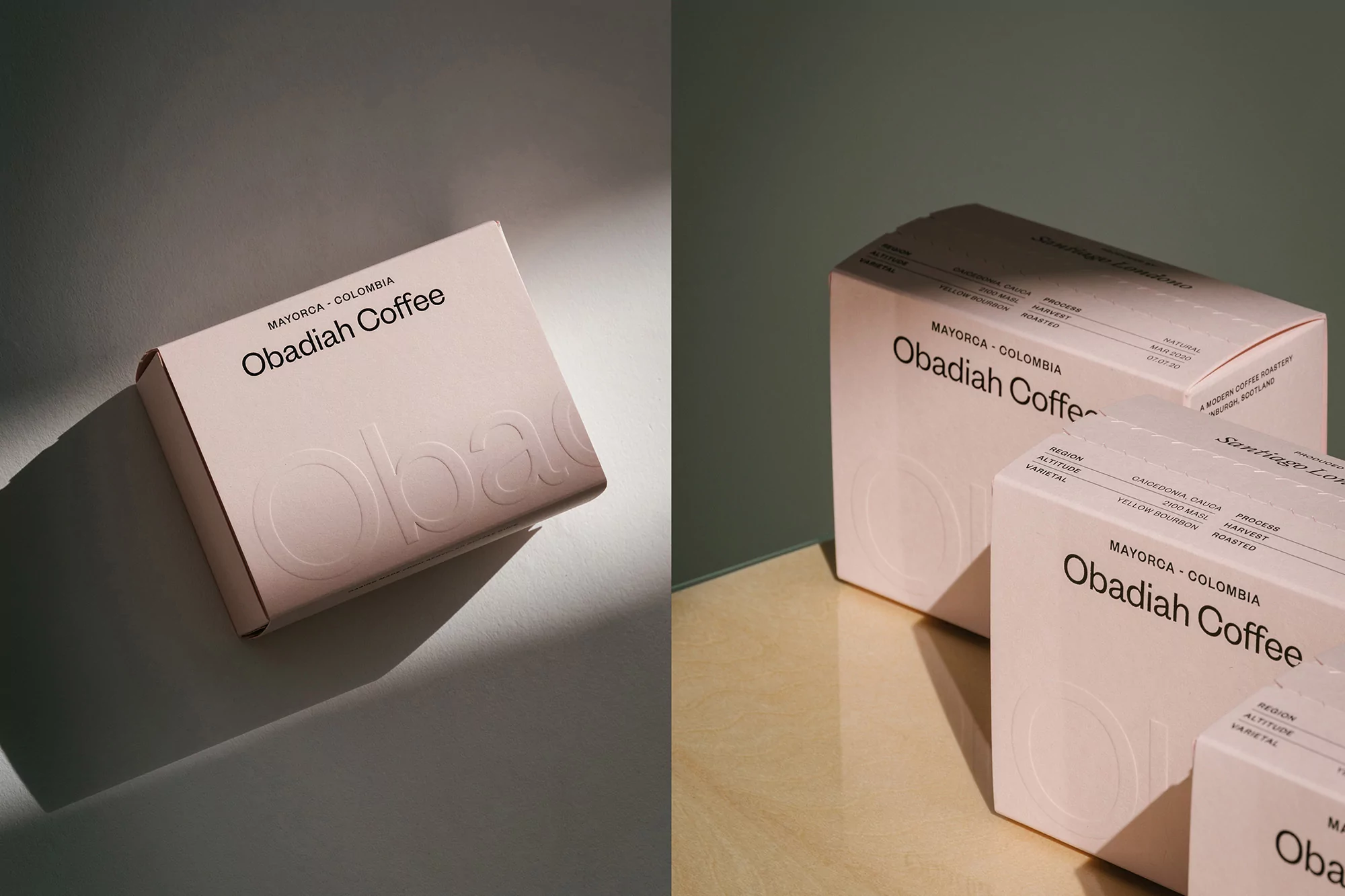 Still life shot of Obadiah Coffee boxes in soft pink, arranged on a reflective surface under a soft, diffused light creating shadows.