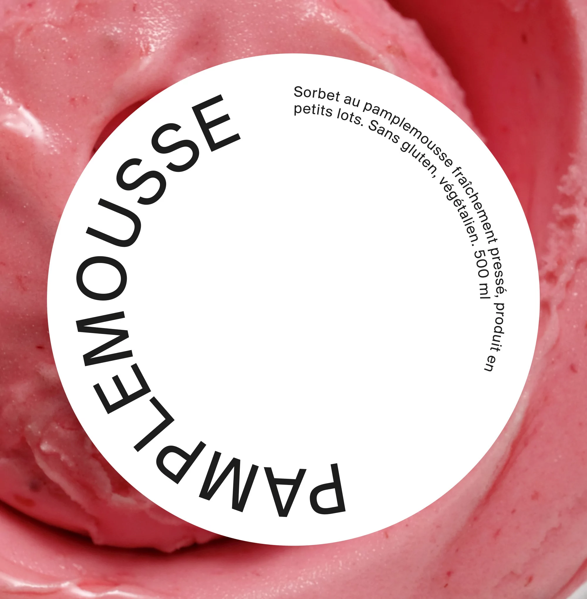 Close-up of pink grapefruit sorbet with white label reading "Pamplemousse" in black text. Sorbet is in soft focus.