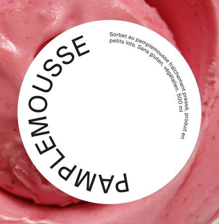Close-up of pink grapefruit sorbet with white label reading "Pamplemousse" in black text. Sorbet is in soft focus.