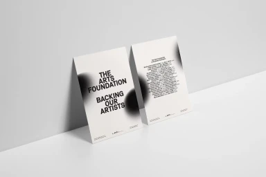Two minimalist white cards leaning against a plain wall featuring black typography and dark blurred gradient circles