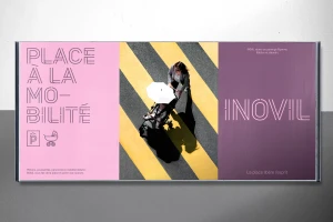 Overhead billboard display featuring a woman walking a stroller across striped pavement between pink and purple panels.