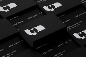 Stacks of black business cards featuring white typography and brand identity design against a dark background