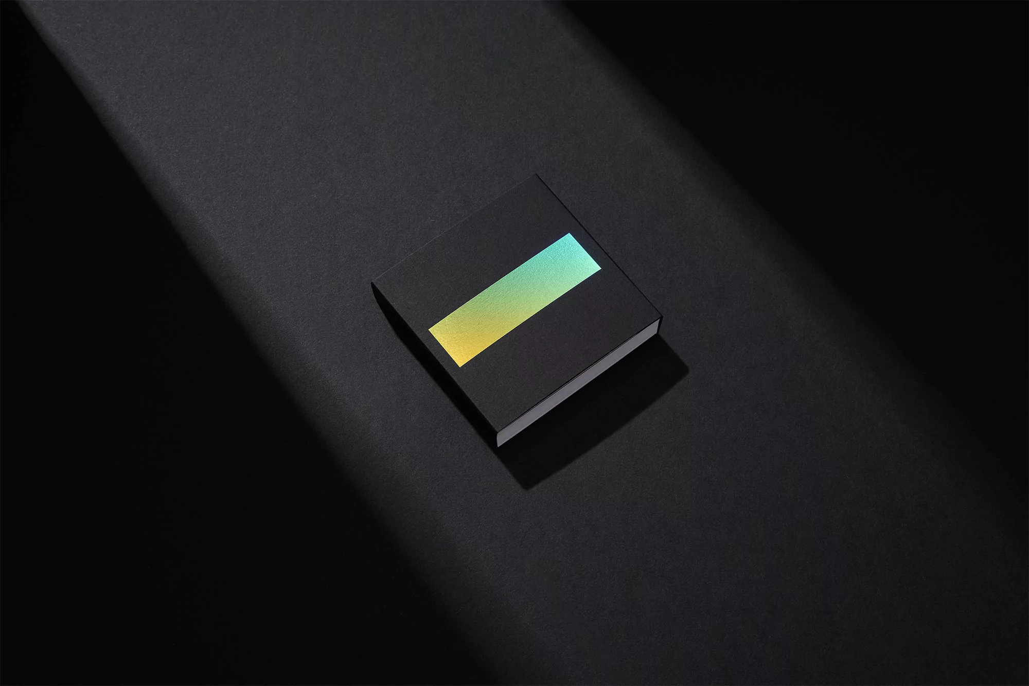 Black box with a gradient stripe on a dark background, featuring a beam of light shining across the surface.