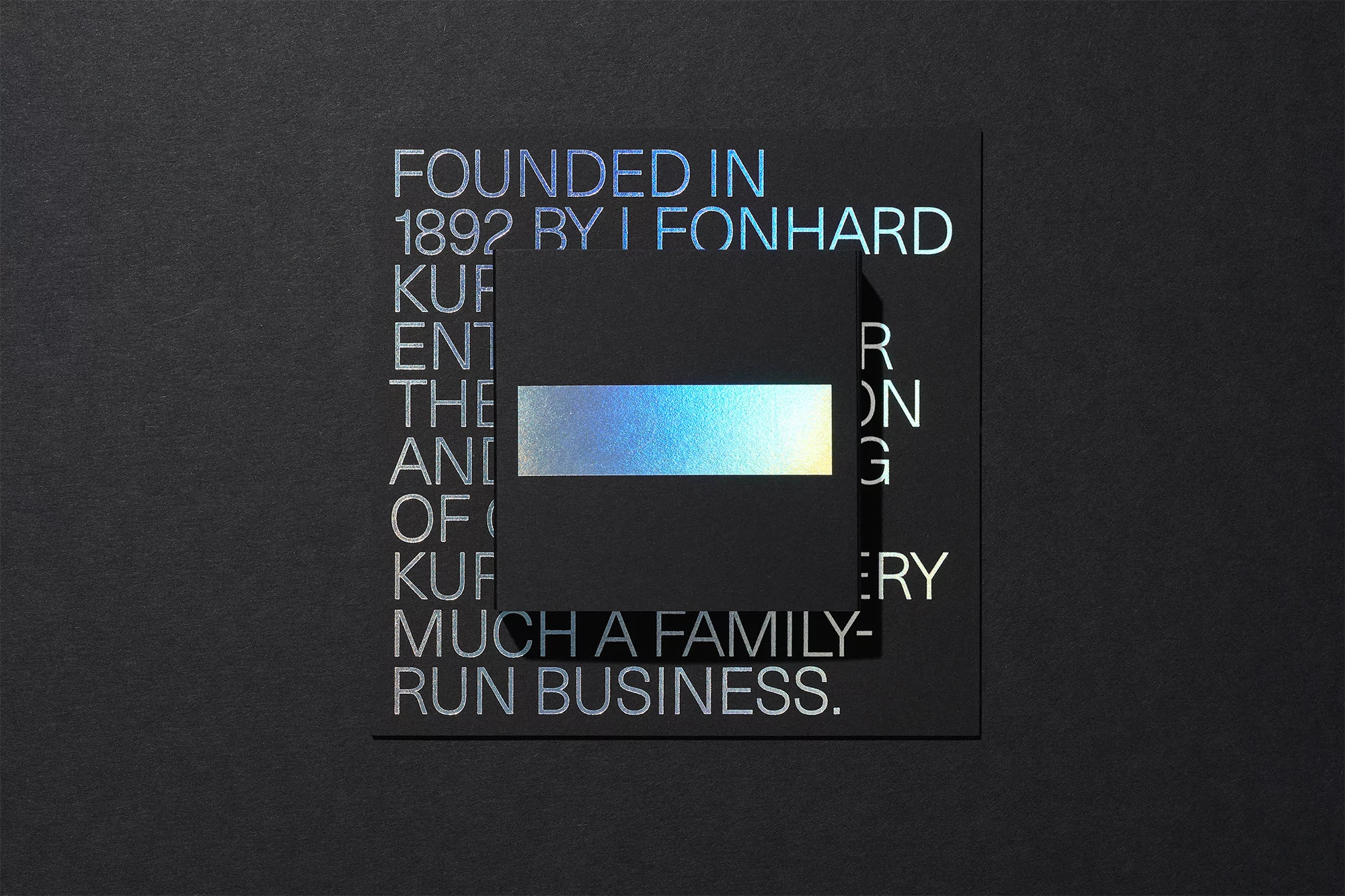 Close-up of a black card featuring holographic text and a partially obscured holographic rectangle, all on a textured black background.