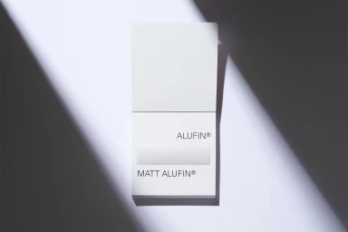 White paper sample card featuring Alufin branding under diagonal harsh light