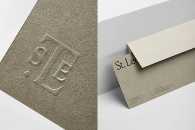 Embossed monogram logo on textured grey paper stationery alongside a folded envelope for St. Leo brand identity