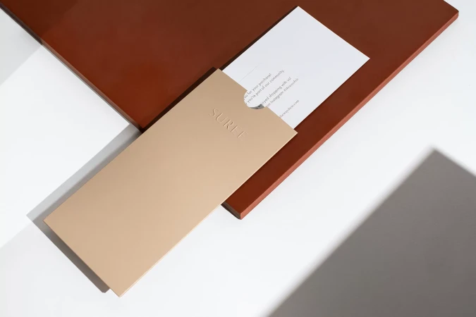 Branded stationery and envelope with embossed logo resting on a terracotta panel against a white surface