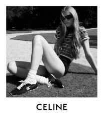 Model Rebecca Leigh Longendyke in striped top and sneakers seated outdoors on a lawn for Celine Fall 2025 campaign