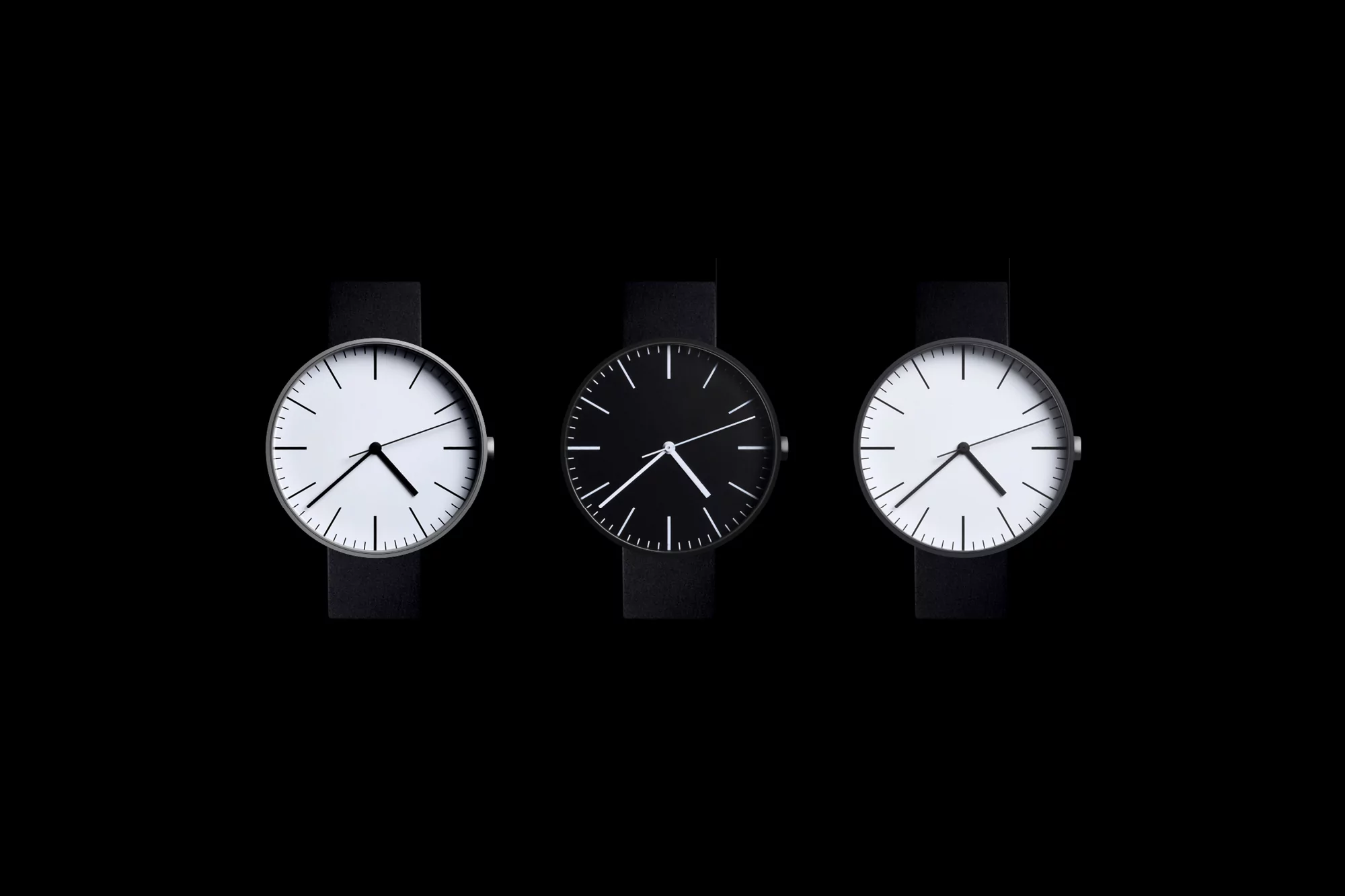 Three wristwatches with black straps, each displaying a different face color (white, black, white), arranged against a black background.