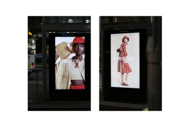 Two backlit outdoor advertising panels displaying Oroton brand fashion campaigns on a city street at night.