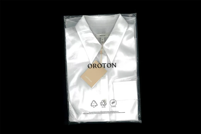 White collared shirt inside a clear plastic packaging bag with a beige brand tag hanging from the collar.