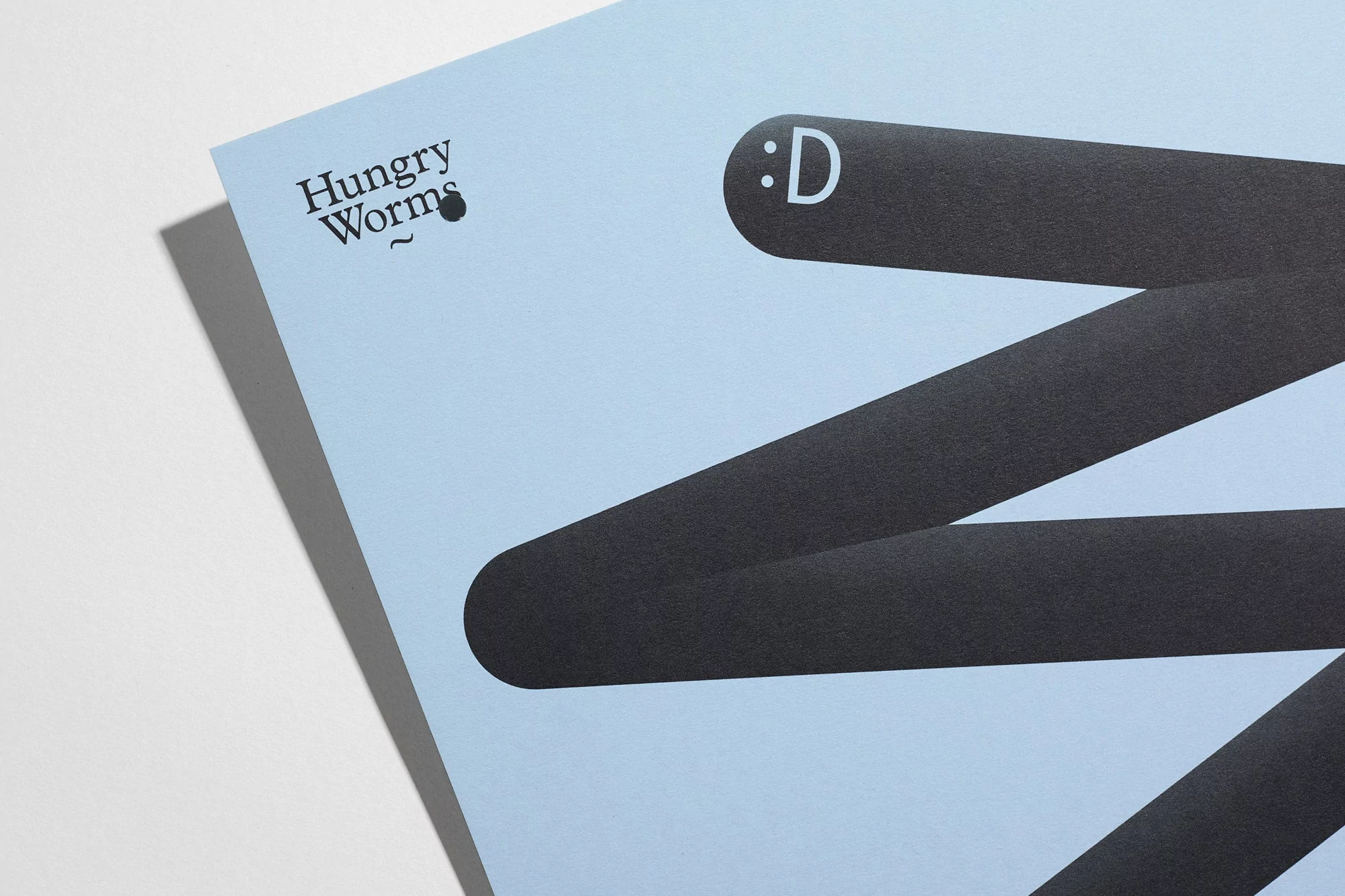 Graphic art on light blue paper shows black rounded-end rectangles arranged diagonally across the frame and logo text "Hungry Worms".