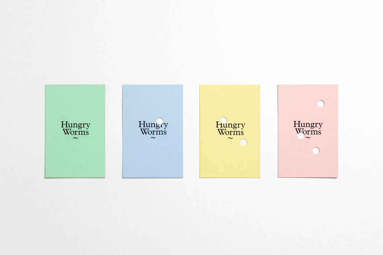 Four pastel-colored paper cards with punched holes and Hungry Worms typography set against a white background.