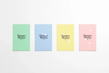 Four pastel-colored paper cards with punched holes and Hungry Worms typography set against a white background.