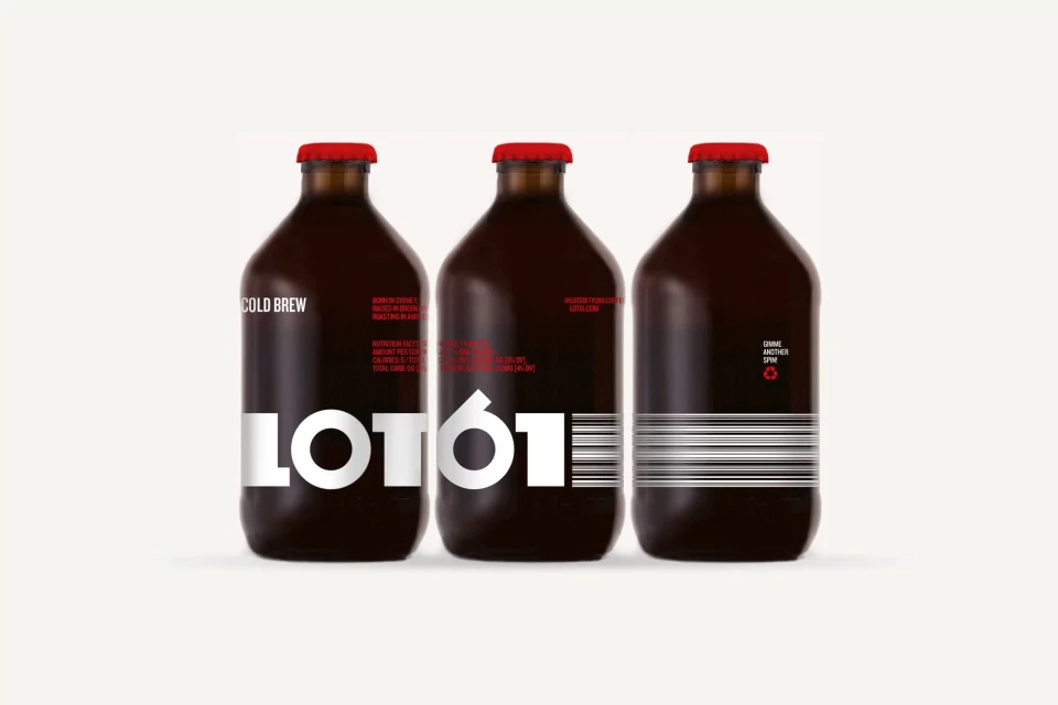 Three brown glass bottles of cold brew coffee with red caps and white labels, arranged closely on a seamless bright white backdrop.