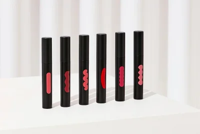 Six black cylindrical tubes with colorful organic shape cutouts arranged in a diagonal line on a white surface.