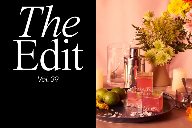 Still life shot of cocktail cubes, limes, shaker, flowers on a black tray, with 'The Edit Vol. 39' text overlay, on a split black and pink background.