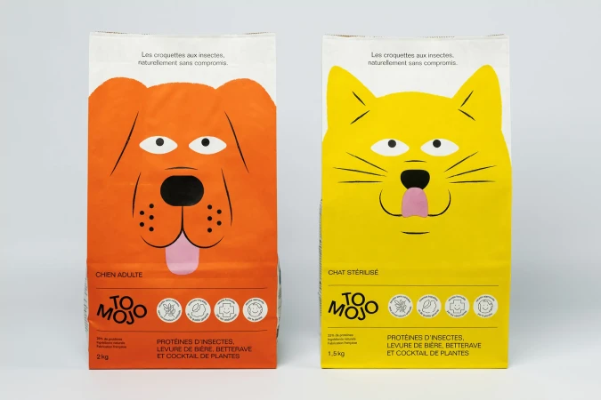 Two packages of pet food with cartoon images: orange dog food and yellow cat food. Each package features the 'To Mojo' brand name.