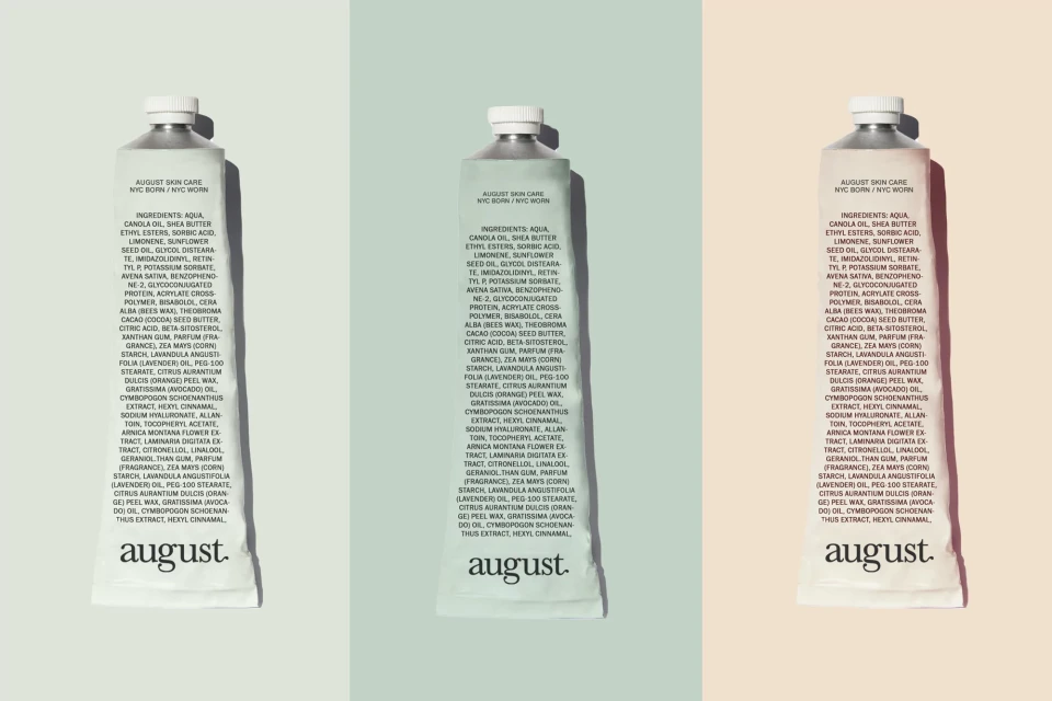 Three tubes of August Skin Care cream in white and silver with visible ingredient list and product information, displayed against split pastel background.