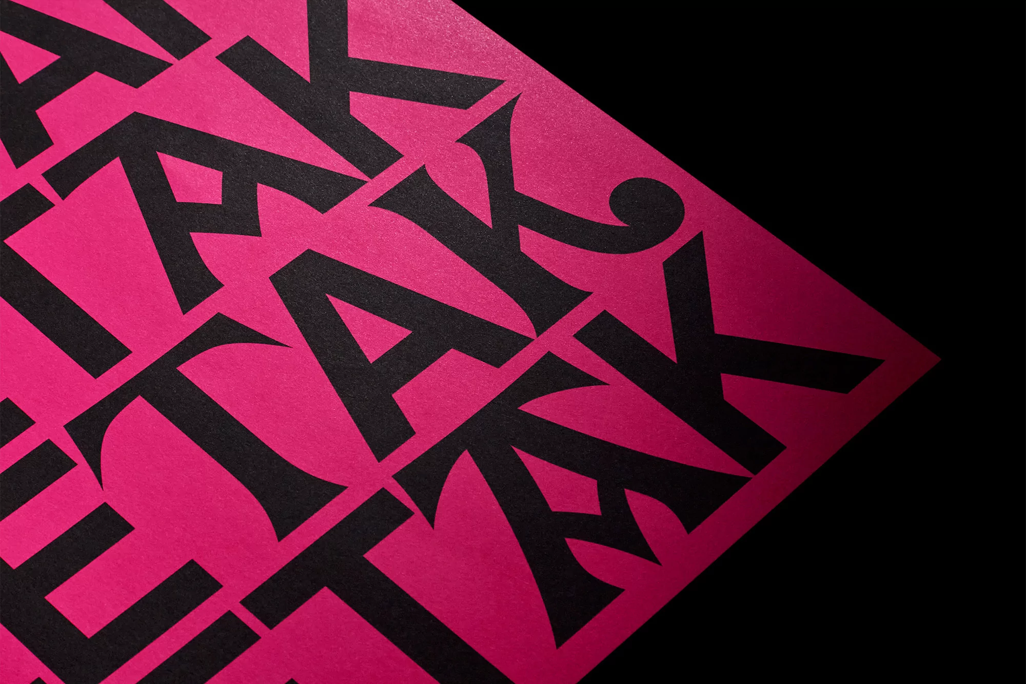 Abstract typography art on diagonally split background showing pink texture and black letters in an all-over pattern.