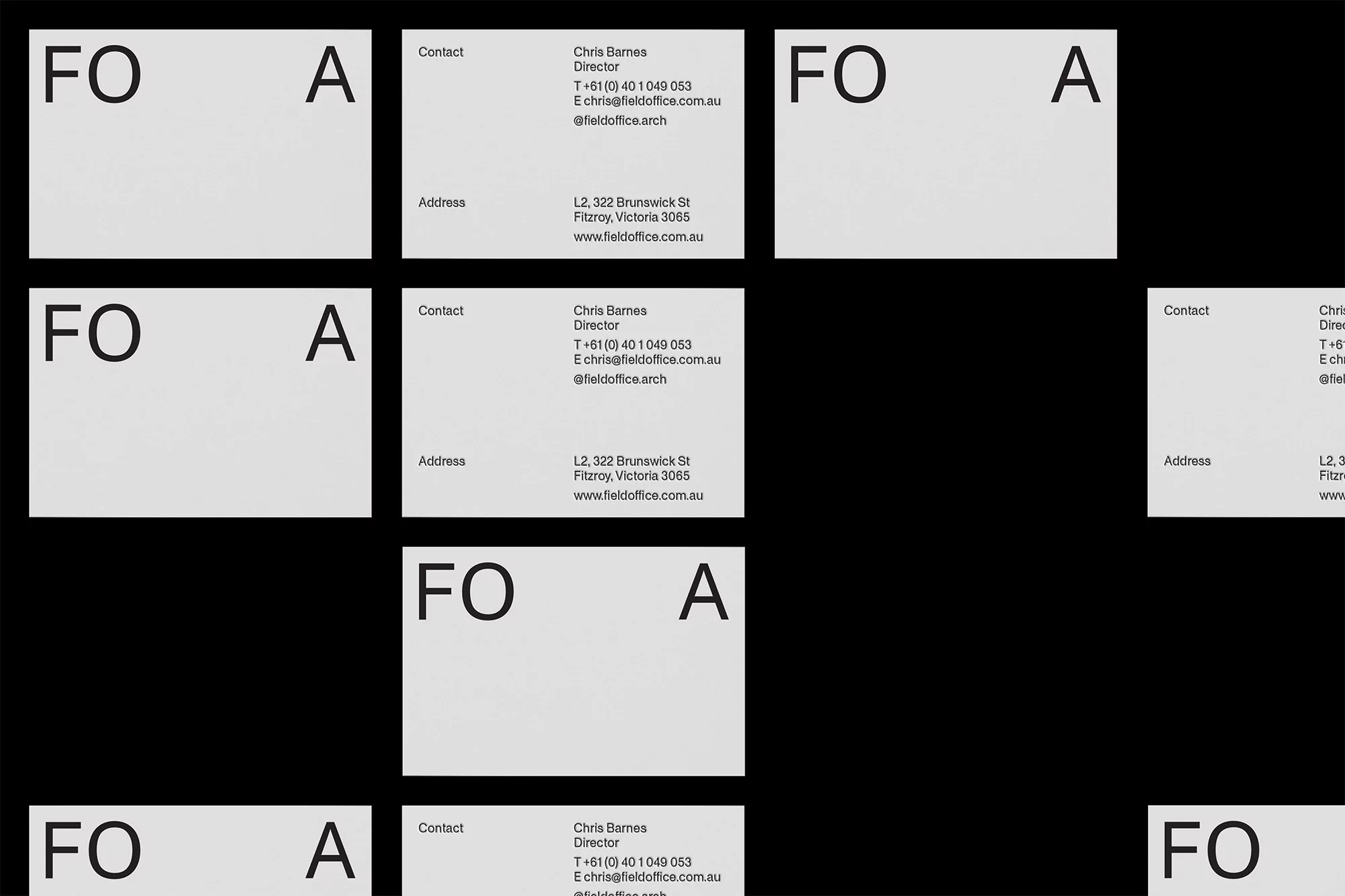 Collection of business cards on a dark background, featuring company logo, contact information, and street address in a minimalist design.