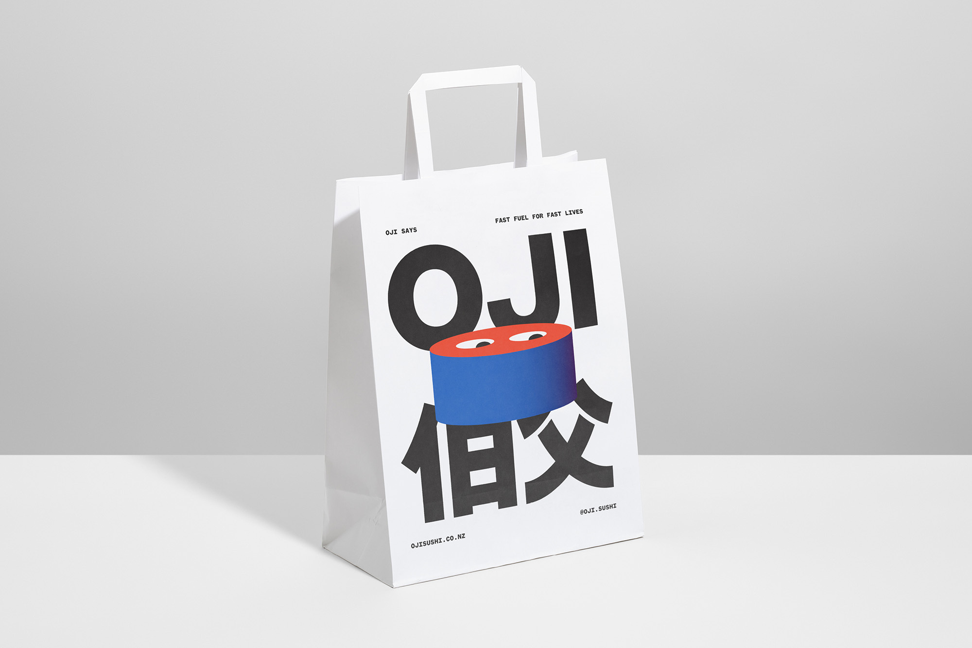 White paper shopping bag stands on a white surface featuring black and blue graphics, minimalist design, and a modern aesthetic.